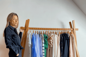 Jeune femme souriant devant un portant de vêtements