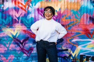 Jeune fille souriante devant un mur coloré