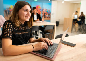 Étudiante souriante qui tape sur le clavier de son ordinateur portable