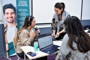 Une femme anime un atelier d'enregistrement de podcast auprès de deux étudiantes de l'école ISEFAC